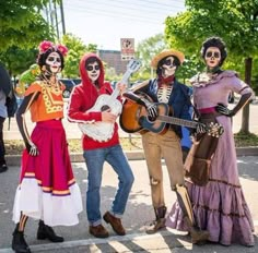 three people in skeleton costumes are holding guitars and standing on the side of the road