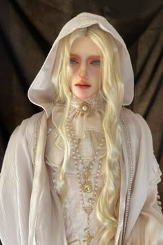 a doll with long blonde hair wearing a white dress and pearls on it's head