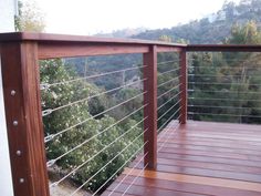 a wooden deck with metal railing and trees in the background