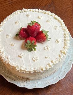 three strawberries on top of a white cake