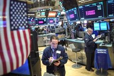 two men standing in front of an american flag on the floor of a stock market