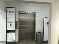 an elevator in a building with stainless steel doors and signs on the wall next to it