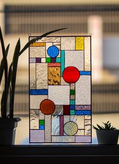 a potted plant sitting on top of a window sill next to a stained glass panel