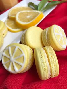 some lemon cookies are on a white plate next to sliced lemons and a red cloth