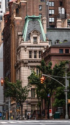 an old building in the middle of a city with tall buildings and trees on both sides