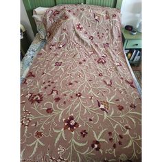 a bed covered in a pink and white bedspread next to a green headboard