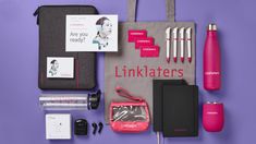 the contents of a travel bag laid out on a purple background, including pens, notebooks and other items