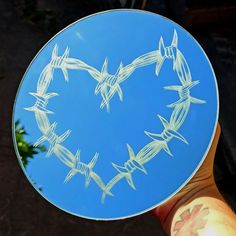 a hand holding a blue plate with barbed wire in the shape of a heart