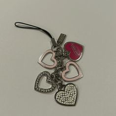 three heart shaped key chains on a white surface with a red tag attached to it