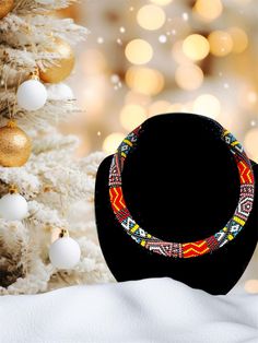 a black hat sitting next to a white christmas tree with ornaments on it and a gold ornament in the background