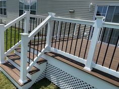 a wooden deck with white railings next to a house