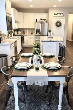 a dining room table set for four with plates and place settings on it in front of an open kitchen