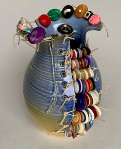 a blue vase filled with lots of different colored buttons and pins on it's side