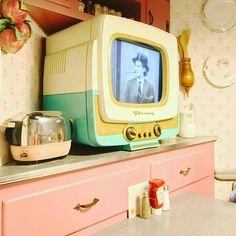 an old tv sitting on top of a pink dresser