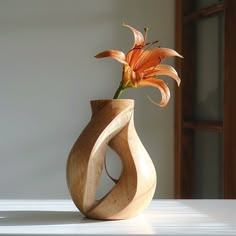 a wooden vase with an orange flower in it