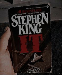 a person holding up a book about stephen king's novel, the heist