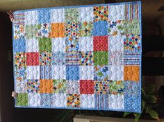 a person holding up a colorful quilt