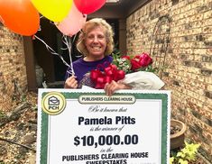 a woman holding a large check for $ 10, 000 in front of her house