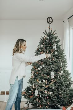 a woman decorating a christmas tree in her living room