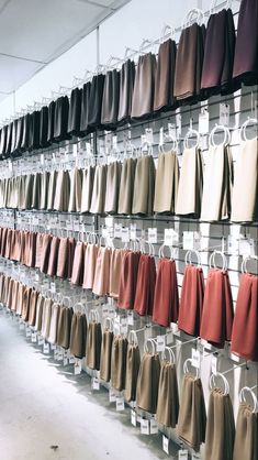 a wall full of different colored pants hanging from hooks on it's sides in a store