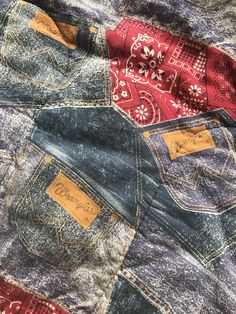 an old pair of blue jeans with red and white patches on them, sitting on top of each other