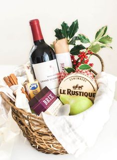 a basket filled with lots of different types of food and wine on top of a table