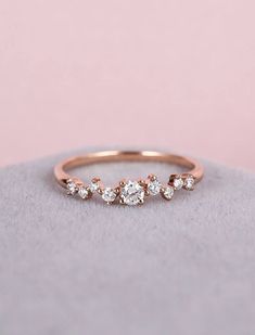 a rose gold ring with three small diamonds on the side, sitting on top of a rock