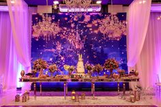 an elaborately decorated stage with chandeliers and flowers on the table for a wedding reception