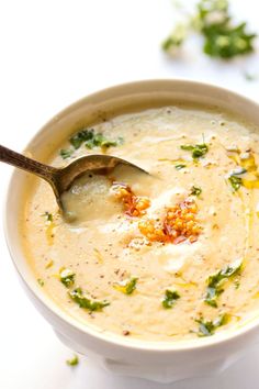 a white bowl filled with soup and garnished with parsley on the spoon