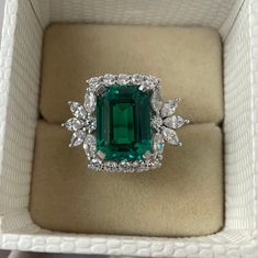 an emerald and diamond ring in a box