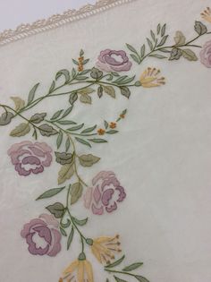 an embroidered tablecloth with flowers and leaves on white linen, closeup view from the bottom