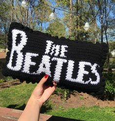 someone is holding up a knitted pillow that says the beatles