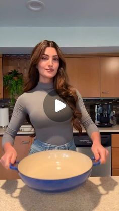 a woman standing in a kitchen holding a bowl