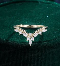 a gold ring with white stones on it sitting on top of a green velvet bag