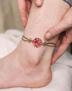 a woman is getting her foot tattooed with a flower on the bottom of her ankle