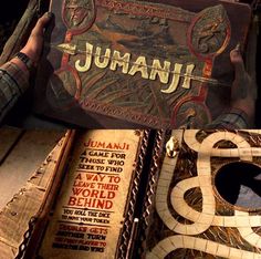 a person holding up a book with the title jumanu written on it in front of them