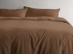 the bed is made with brown sheets and pillows