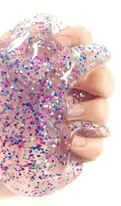 a hand holding a pink and purple glitter ball