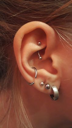 an ear with three different piercings attached to it's sides and two smaller ones behind the ear