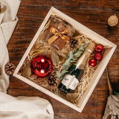 a bottle of wine in a wooden box with christmas decorations on the table next to it