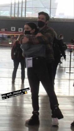 two people are standing in an airport with their arms around each other and one person is taking a selfie