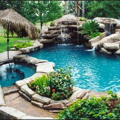 an outdoor swimming pool with waterfall and landscaping