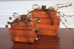 two wooden boxes sitting on top of a hard wood floor covered in string and bows