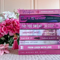 a stack of books sitting on top of a table next to a vase with flowers