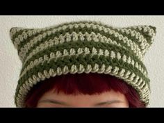 a woman with red hair wearing a green and white crocheted hat