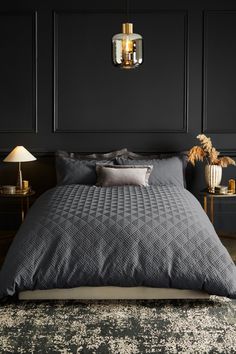 a bedroom with black walls and grey bedding