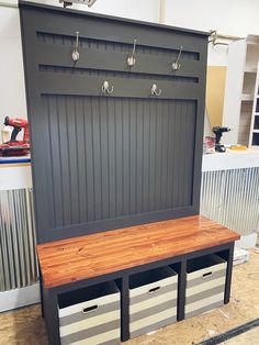 a bench with two storage bins underneath it and some hooks on the wall behind it