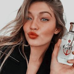 a woman holding a bottle of perfume in front of her face