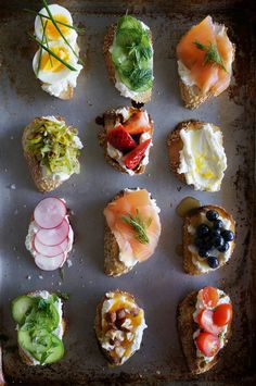 an assortment of small sandwiches on a baking sheet with vegetables and meats in them