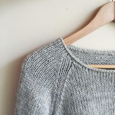 a gray sweater hanging on a wooden hanger